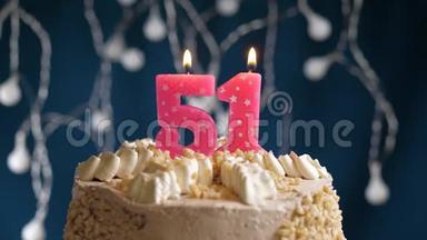 生日蛋糕，<strong>51</strong>号粉红色燃烧蜡烛在蓝色的背景上。 蜡烛吹灭了。 慢速运动和特写镜头